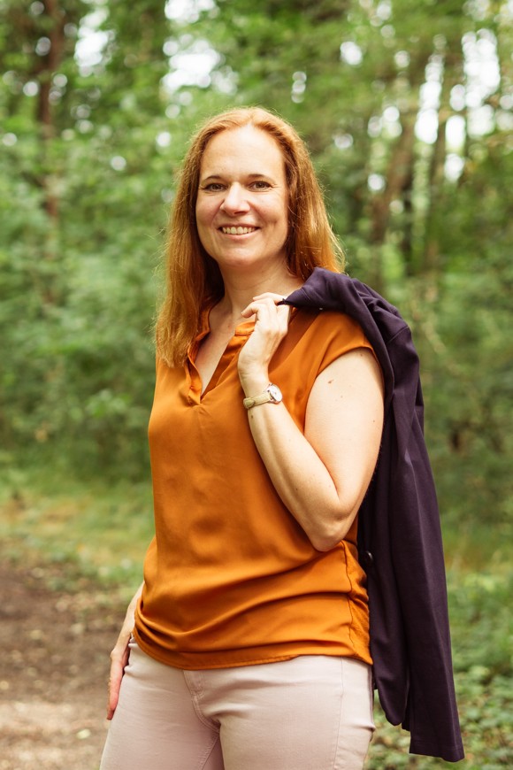 Eine Frau in einer hellbraunen Bluse. Das ist Alexandra Vukits